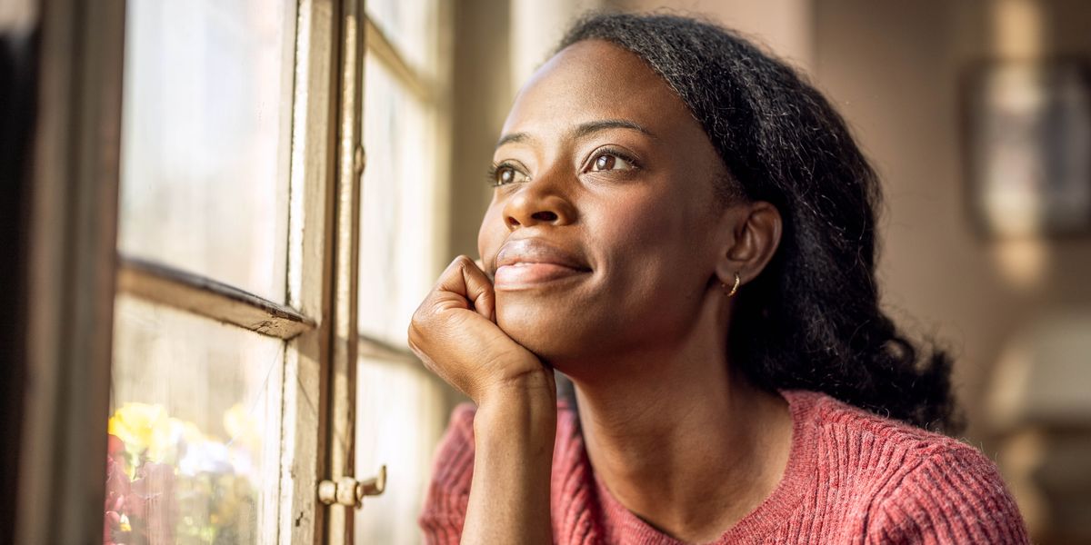 A young woman peacefully gazing out a window.