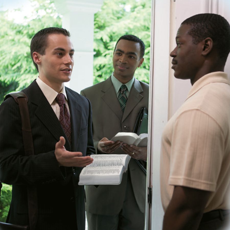A Bible student shares a Bible message with a man as his teacher looks on