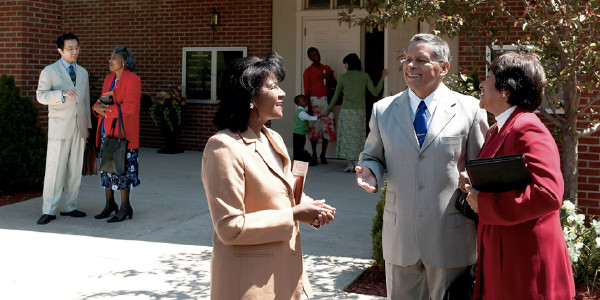 Brothers and sisters happily talking with one another outside a Kingdom Hall.
