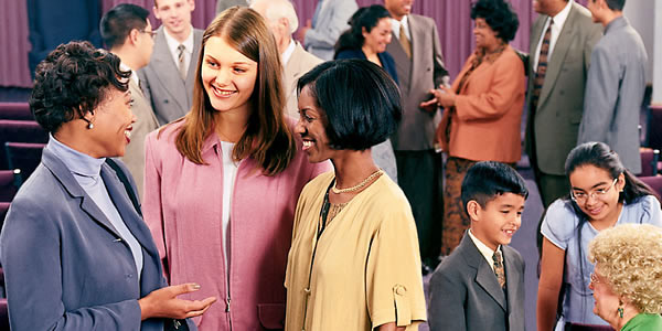 Brothers and sisters conversing happily at a congregation meeting.