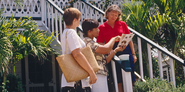 Two of Jehovah’s Witnesses preaching to a woman at her home.