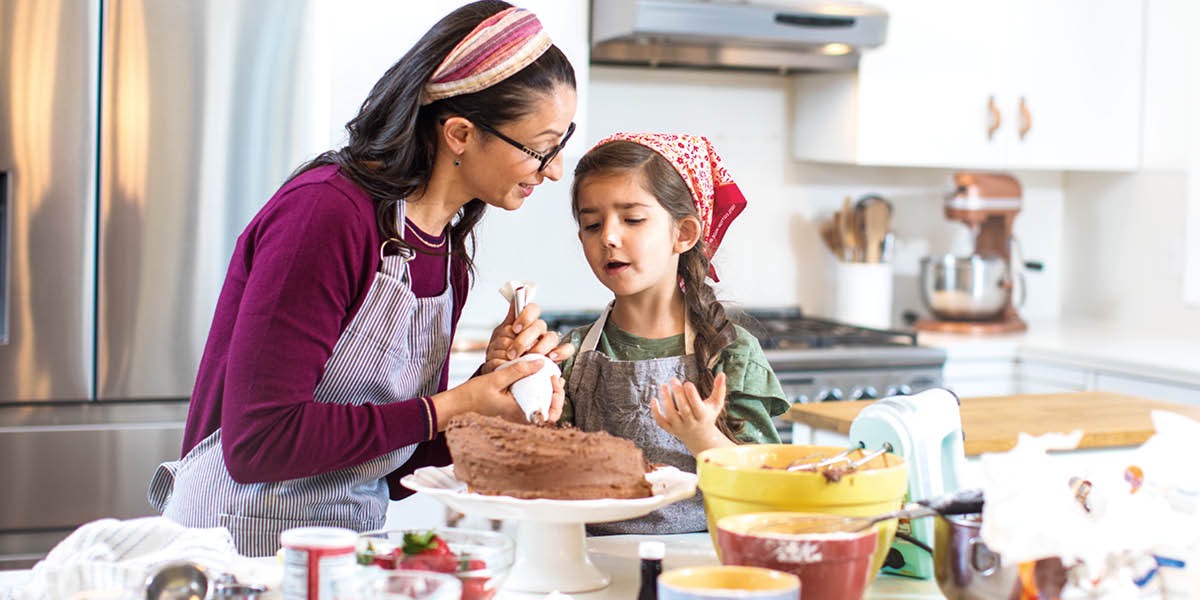A mother helps her daughter who is frustrated because a cake she baked turned out poorly