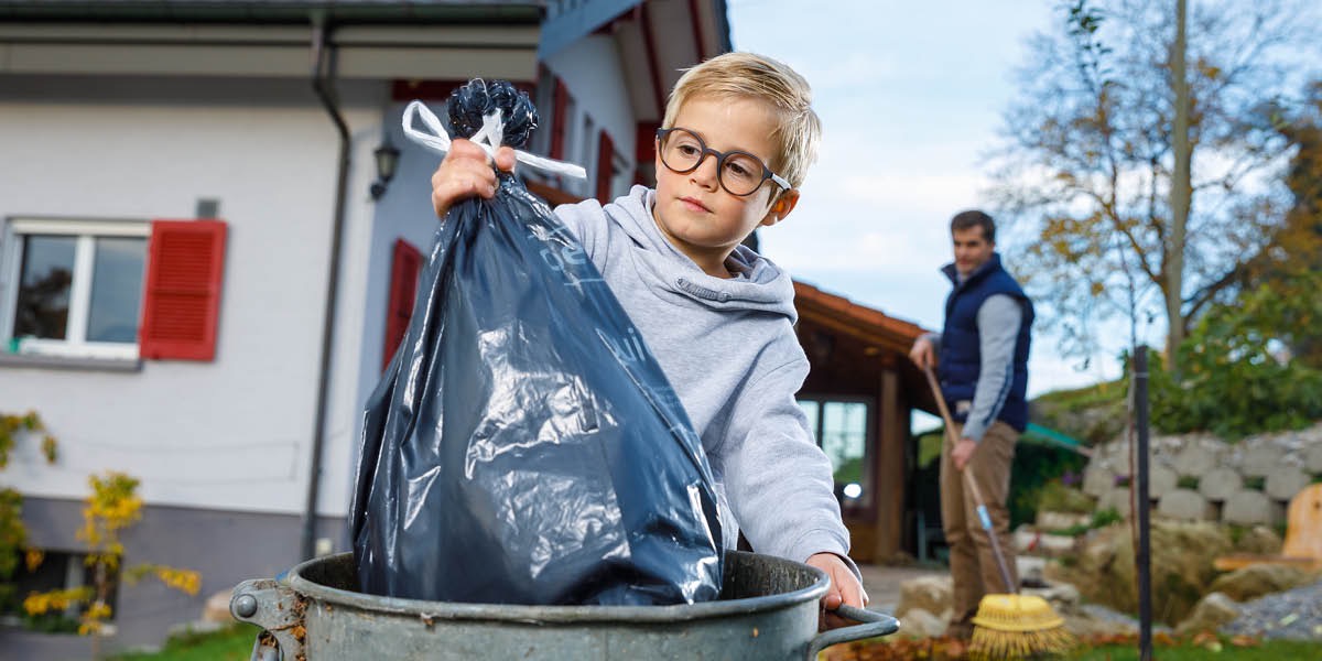 A boy puts trash in a bin