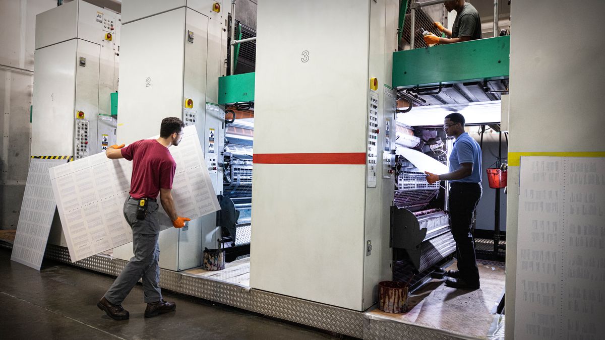 Brothers changing plates and doing maintenance on a large printing press.