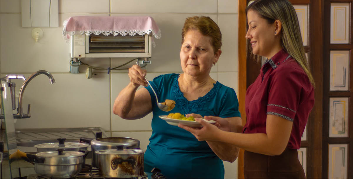 Maria Lúcia dishing up one of her home-cooked meals for a friend.