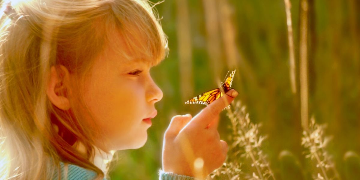 A girl looks at a butterfly