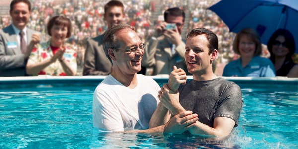 A man being baptized in water at a large Christian convention