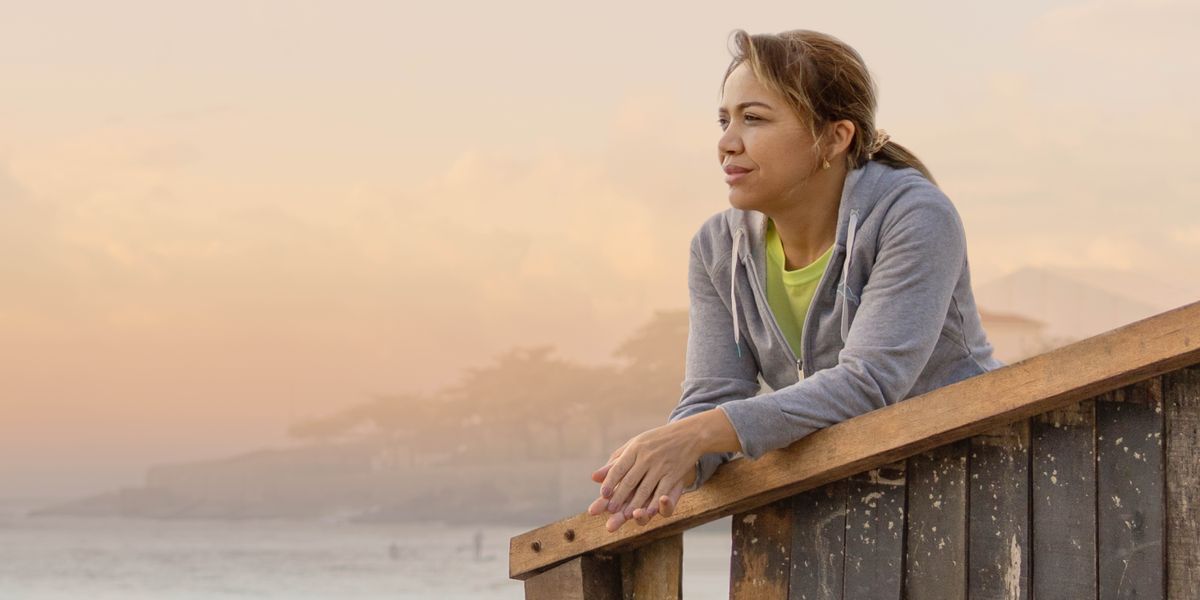 A woman looking hopefully toward the sea at sunset.