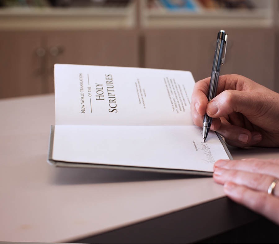 One of Jehovah’s Witnesses writes his name in his personal copy of the Bible