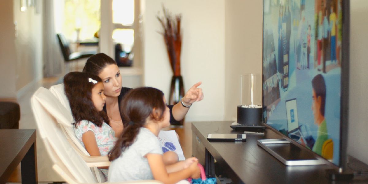 Talita watches a video on jw.org with her mother and her sister; her mother gives audio descriptions