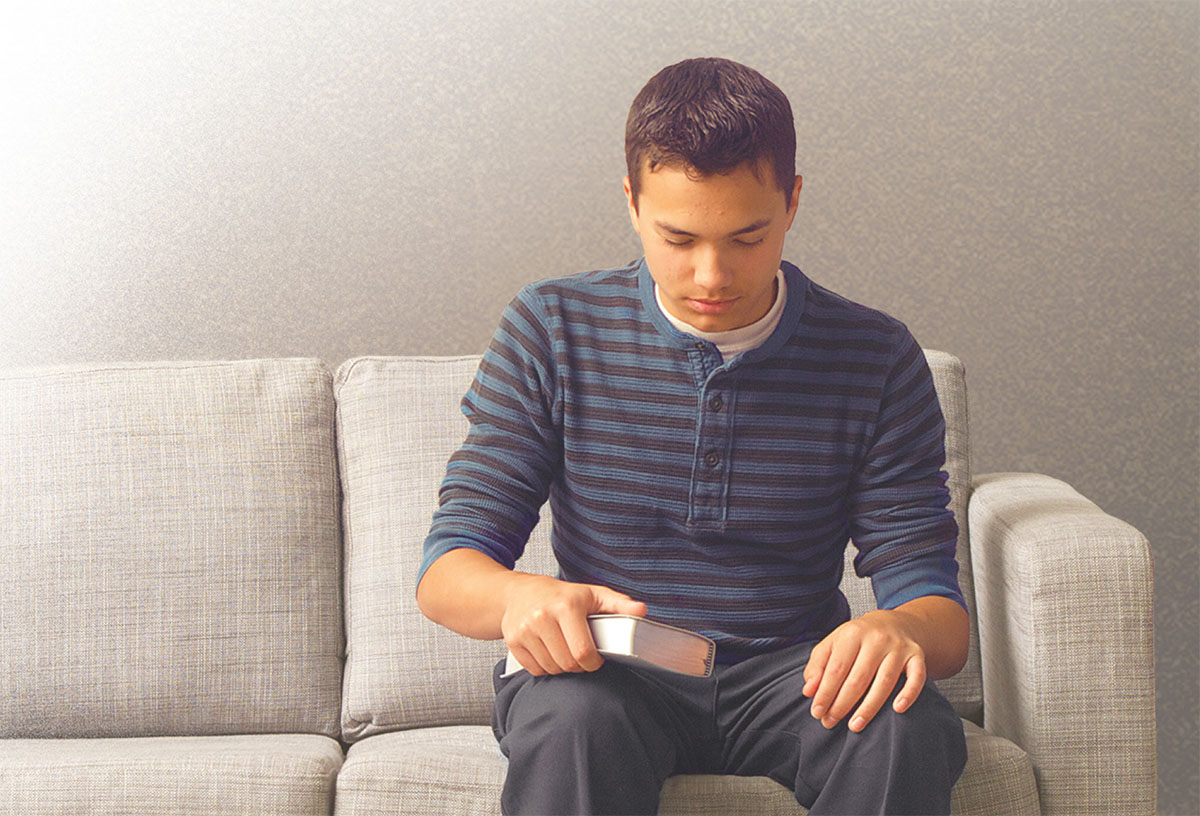 A young brother sits on a sofa and prays