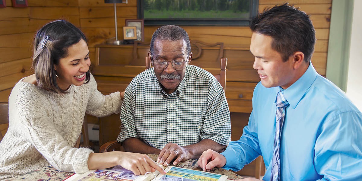 An elderly brother showing a photo album to a young couple.