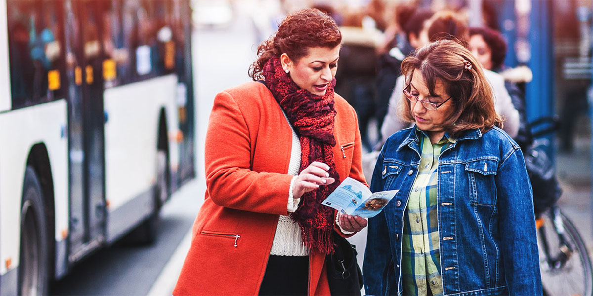 A sister witnessing informally to a woman at a bus stop using the tract ‘Will Suffering Ever End?’