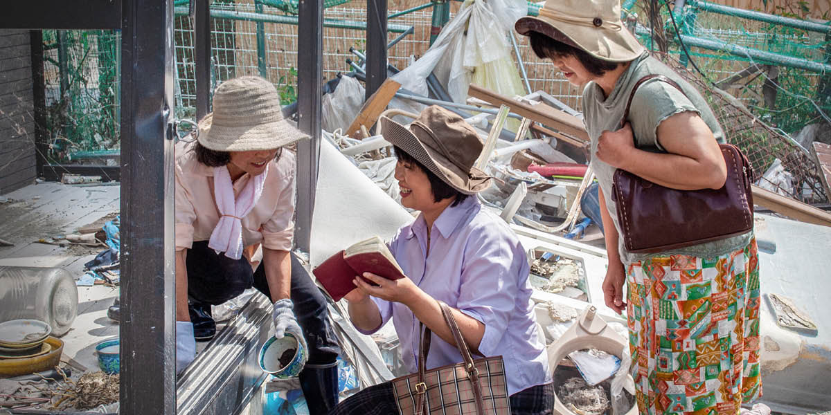 Two sisters preaching to a woman who is cleaning up her debris-filled home after a natural disaster.