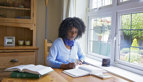Rosalind John writing notes and using research publications during her personal study of the Bible.