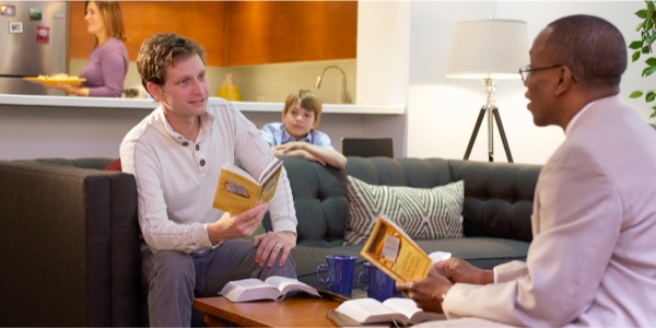 A man, no longer smoking, is having a Bible study; his family is happy