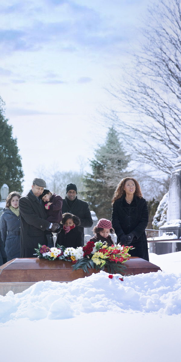 Adults and children gather around a casket at a cemetery