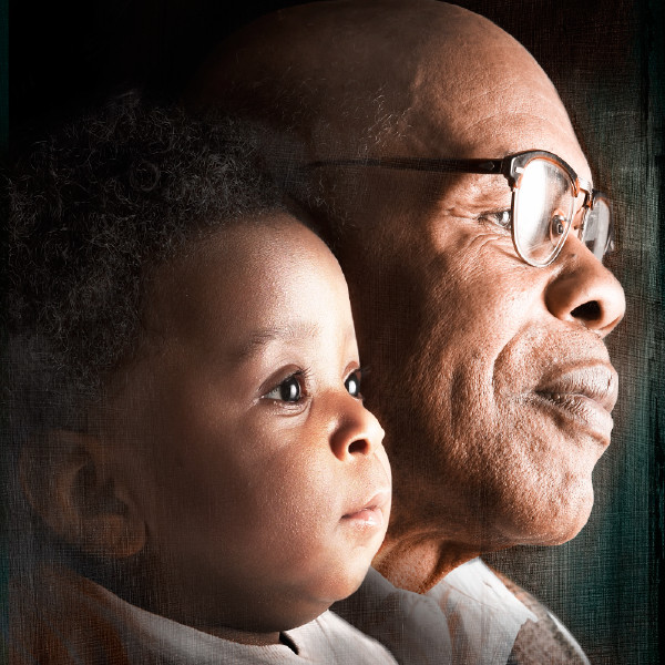 An older man and a baby gaze into the distance