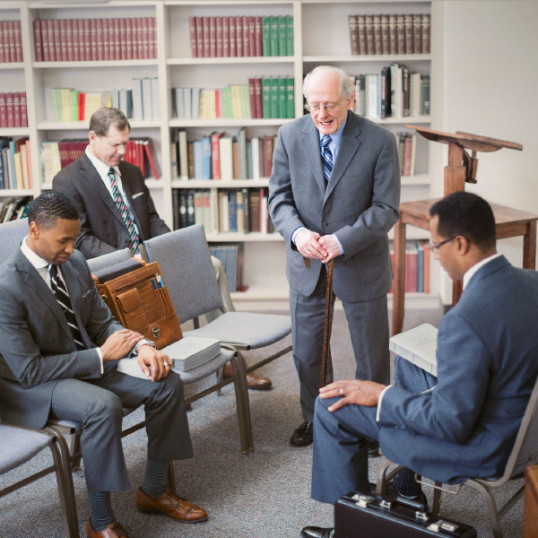 Younger Christian elders bow their heads while an older elder prays
