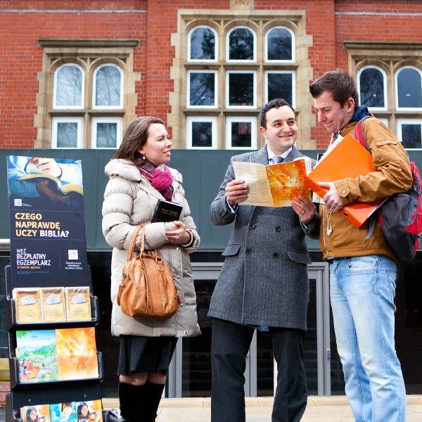 Pawel and Esther Pyzara stand by a literature display cart and speak to a man about the Bible