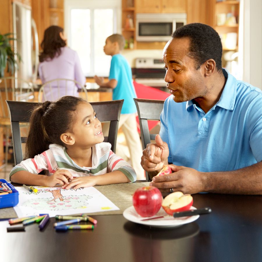 A father uses an apple to teach his daughter about Jehovah