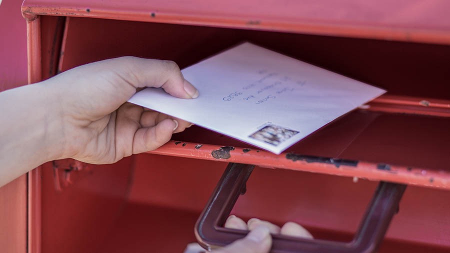 A sister puts a letter in a mailbox