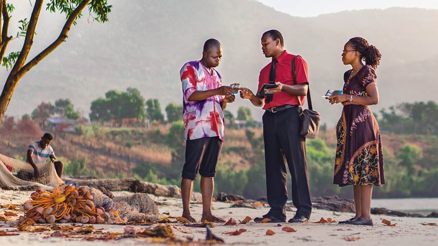 A couple in Sierra Leone give a meeting invitation to a local fisherman