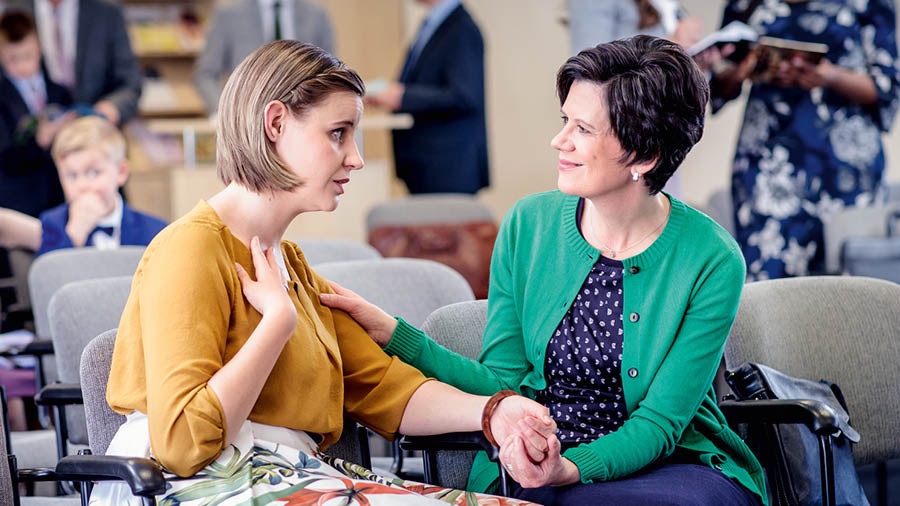 Two sisters talk with each other at the Kingdom Hall and forgive one another