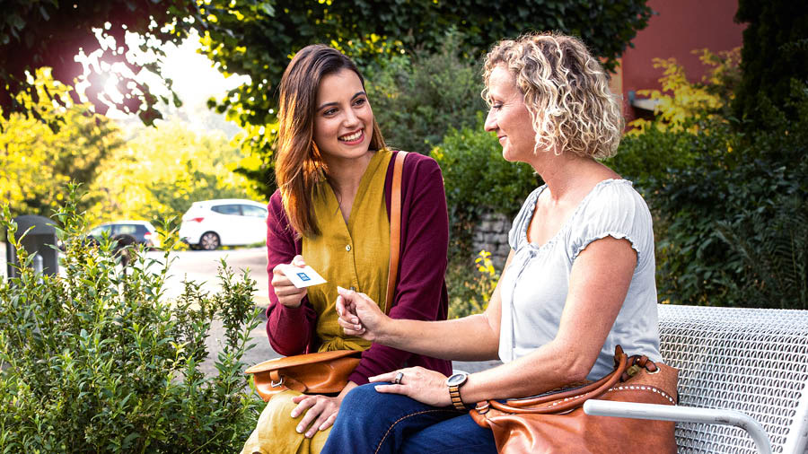 The sister preaching to a woman as they sit on a park bench.
