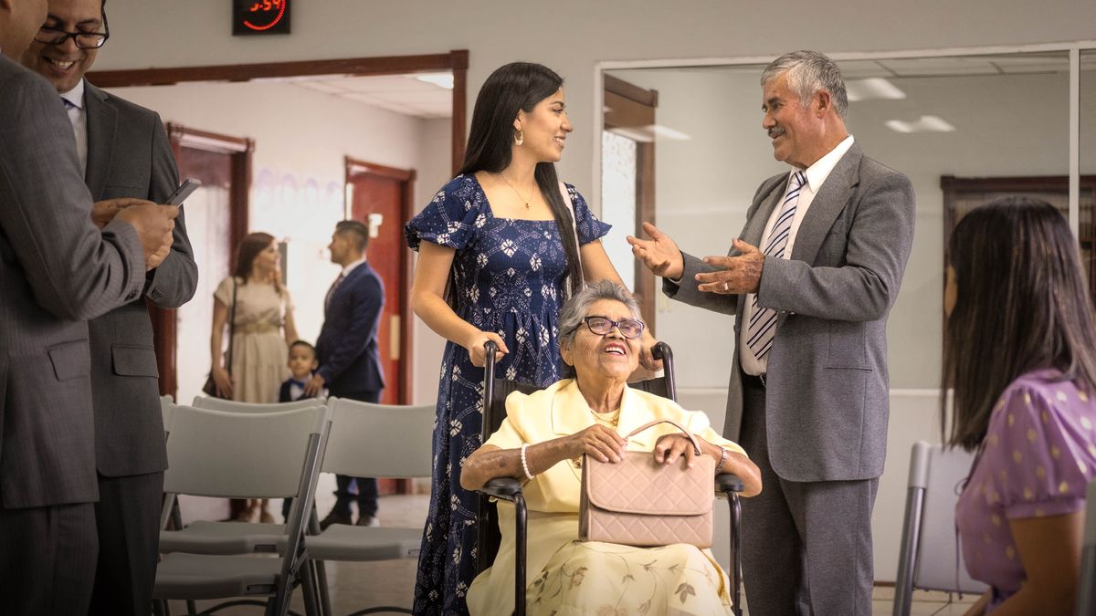 An elder commending a sister who is assisting another sister in a wheelchair.