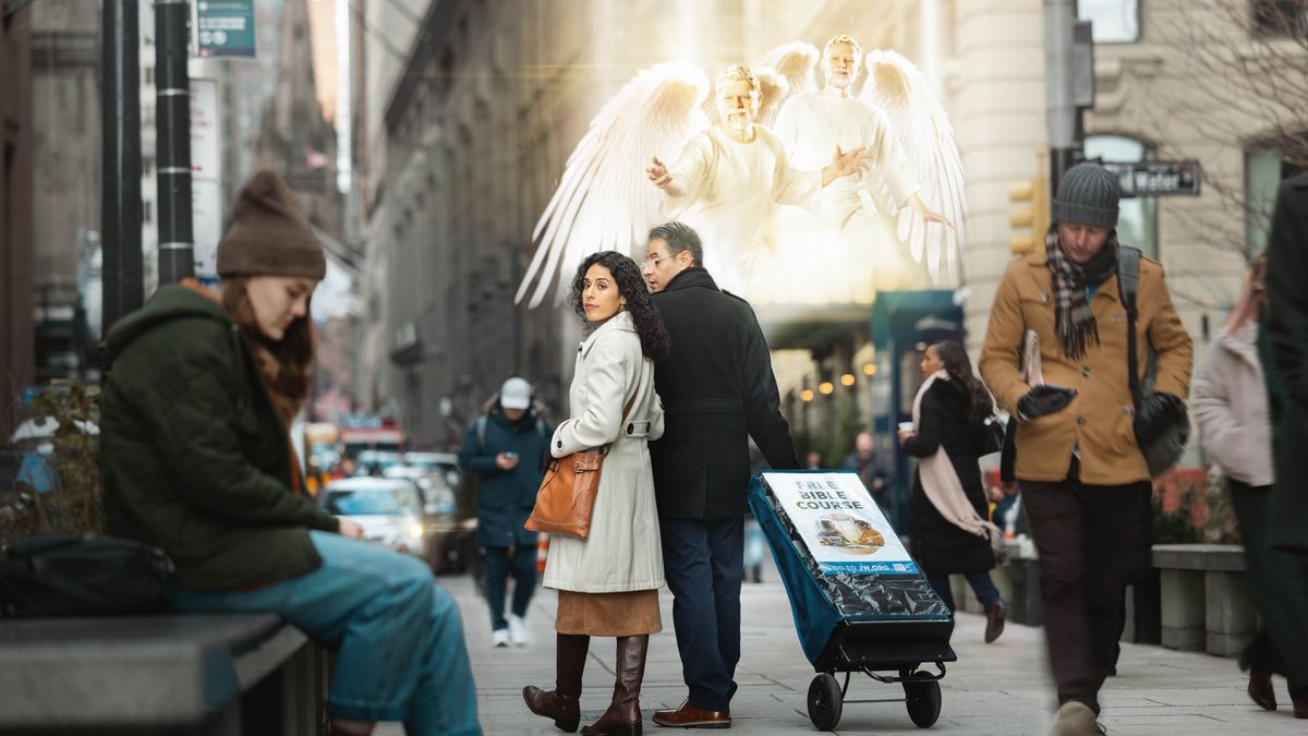 A couple walking with a public witnessing cart on a city street. Angels hover above and direct the sister to notice a distressed young woman sitting on a bench.