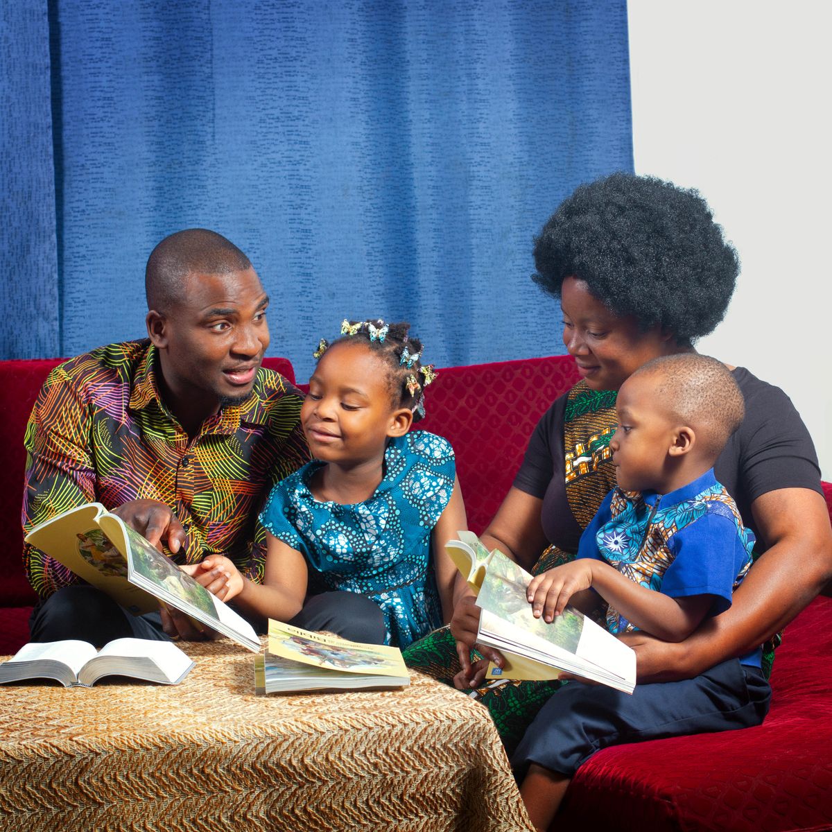 A father conducting family worship with his wife and two young children.
