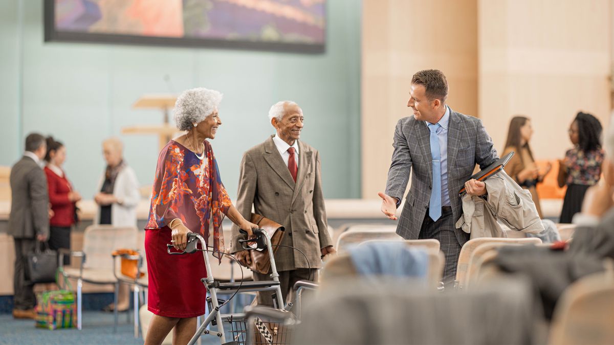 A young brother at a circuit assembly, offering his seats to an older couple.