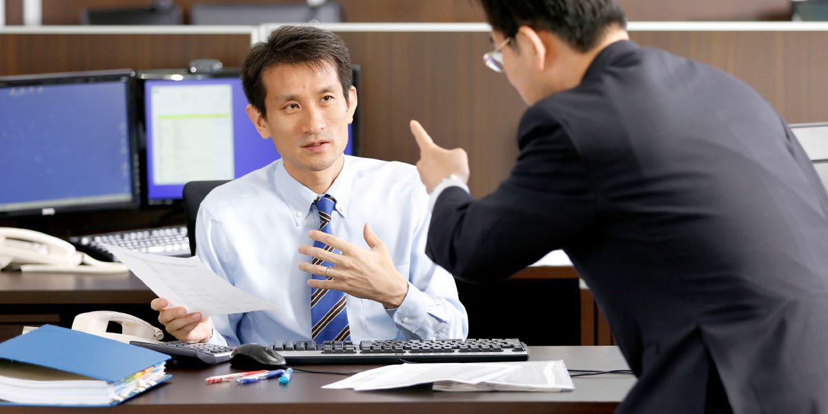 An employer shakes his finger at an employee