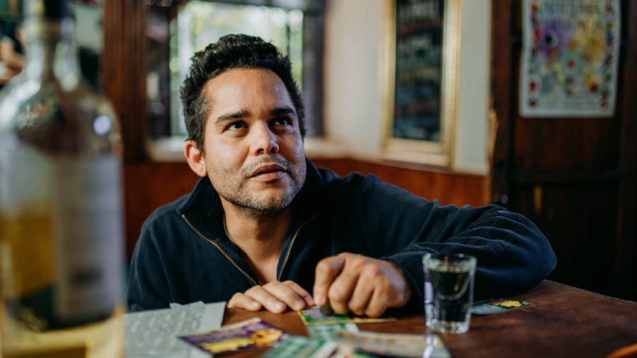 A man looking upward while he scratches a lottery ticket.