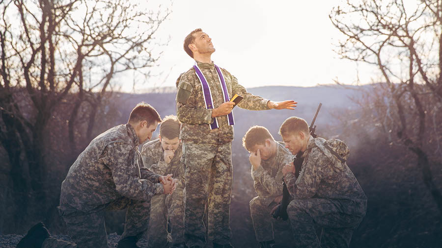A clergyman praying for a group of soldiers.
