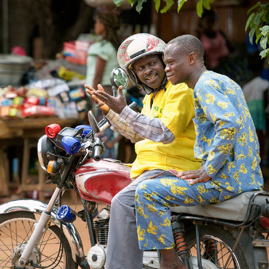 In Benin, Désiré uses an audio player on his motorcycle taxi to preach to a passenger