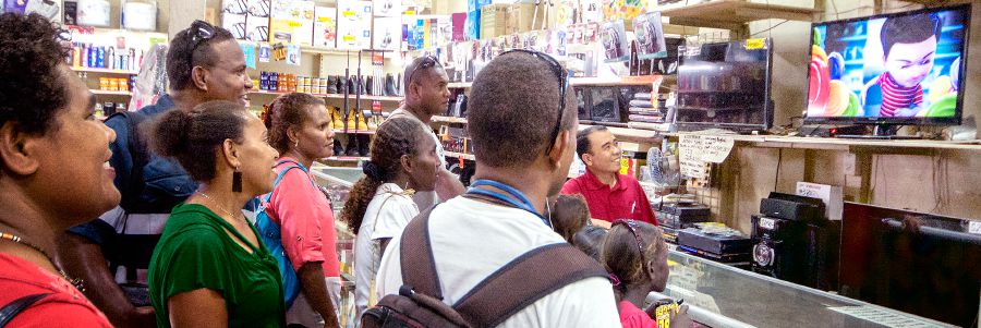 In a store in the Solomon Islands, adults and children watch a video from jw.org