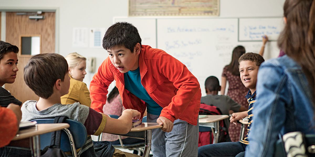 One boy is bullied by another in front of his schoolmates