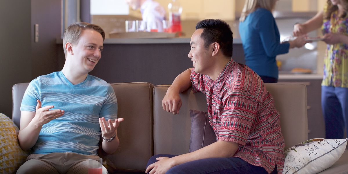 Dos jóvenes conversan sentados en un sofá