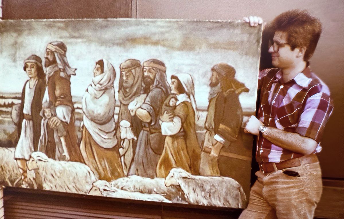 Peter mostrando una de sus pinturas, donde se ven unas familias israelitas caminando con sus ovejas.