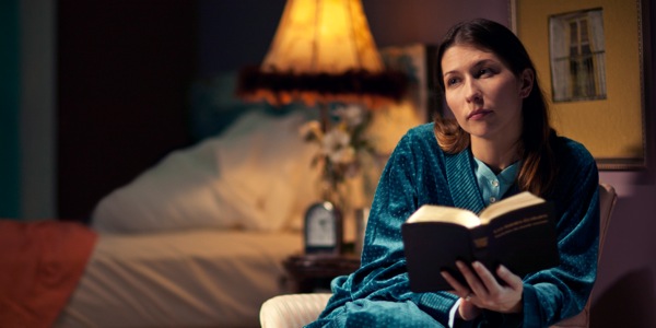 Una cristiana lee la Biblia por la noche y piensa en lo que lee