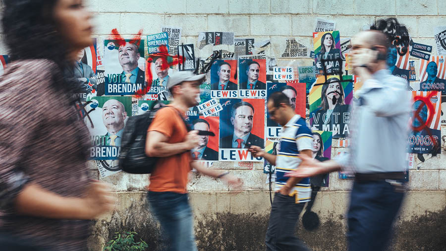 Jendea kanpaina politikoen kartelekin estalitako pareta baten ondotik pasatzen ari da.