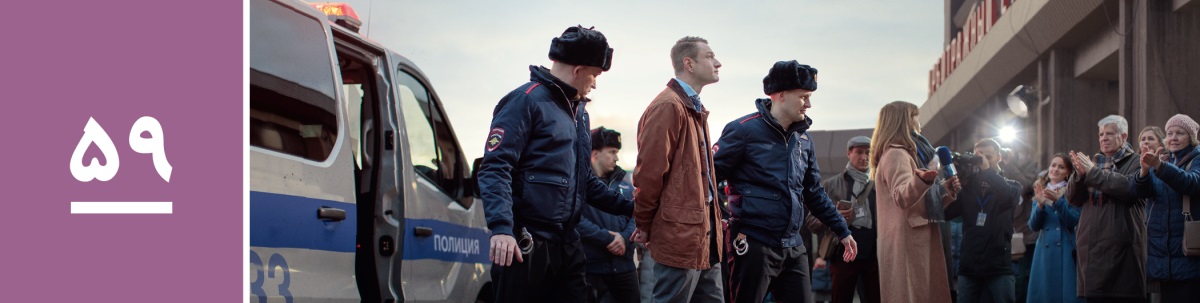 درس ۵۹.‏ دو مأمور پلیس برادری را که دستبند به دست دارد همراهی می‌کنند و گزارشگران و شاهدان یَهُوَه آن‌ها را نگاه می‌کنند.‏