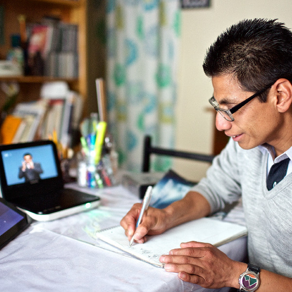 Daniel, un homme sourd, prend des notes en regardant un DVD en langue des signes mexicaine