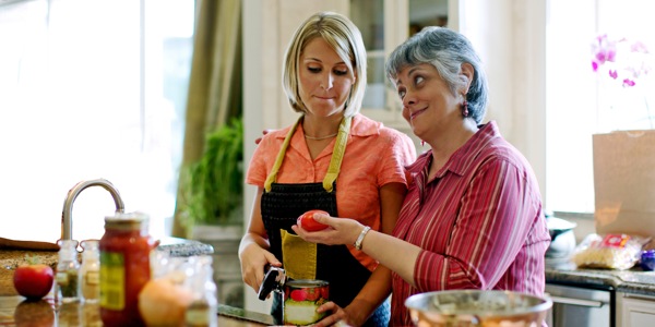 Une belle-mère regarde d’un air désapprobateur la façon de cuisiner de sa belle-fille