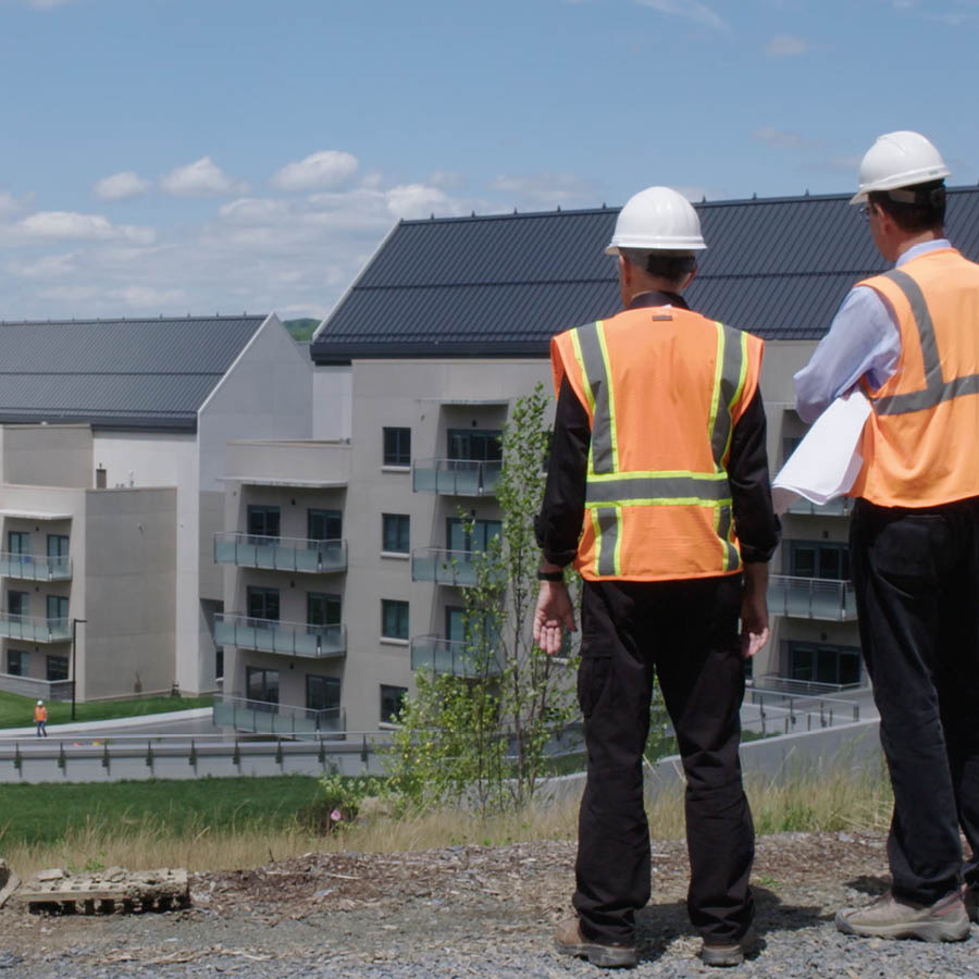 Deux ouvriers regardent des bâtiments neufs sur le site du siège mondial des Témoins de Jéhovah.