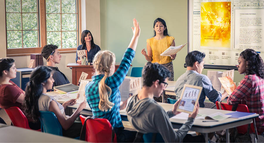 Une jeune sœur présente à ses camarades de classe un exposé en se servant de la brochure « Origine de la vie ». Une élève lève la main.