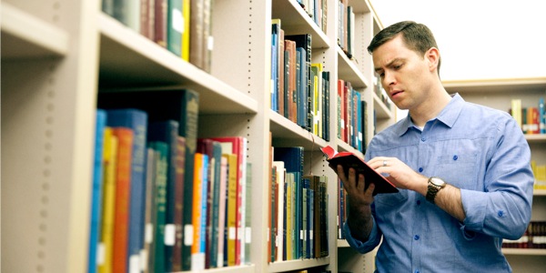 Un homme en train d’examiner la Bible dans une bibliothèque