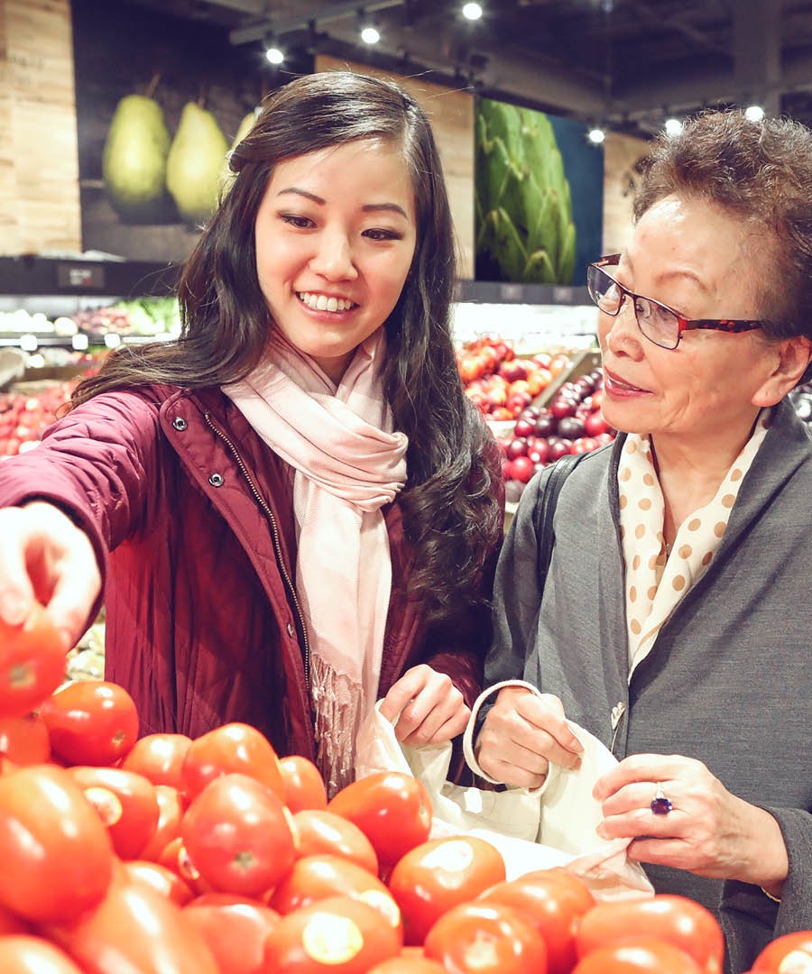 Une jeune femme aide une femme âgée à faire ses courses dans une épicerie